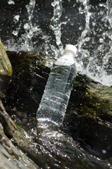 Naklejka na ściany i meble A bottle of drinking water on a clean mountain stream.