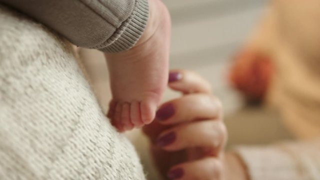 Grandmother tickling small baby feet. Close up slow motion shot