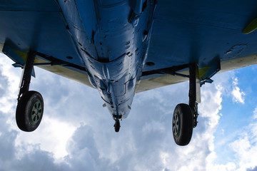 Bottom part of a retro aircraft with undercarriage or chassis, against dramatic sky background, with copyspace for text