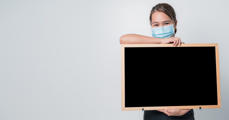 Covid-19 Concept,Asian young woman wearing a hygiene protective mask over her face with a black broad with holding on hand, protect from Coronavirus or Covid-19 epidemic.