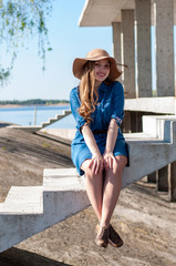 vertical portrait of a positive long-haired blonde on the background of an unfinished concrete bridge