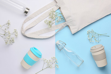 Eco shopping bag with glass bottles and thermo cups on color background