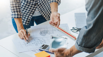 engineer Hand Drawing Plan On Blue Print with architect equipment discussing the floor plans over blueprint architectural plans at table in a modern office.