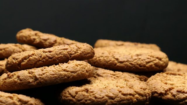 Rotating Close Up Of Fresh Brown Oatmeal Cookies On A Black Plate On A Black Background.