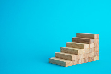 Wooden block stack as stair step on blue background with copy space. Abstract business goal, target, growth or success plan concept.