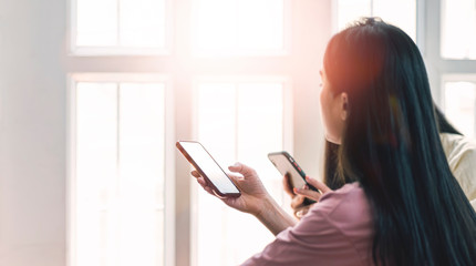 Two young women working from home, using smartphone together.