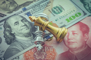 The US and China trade war and currency war concept. Two king chess piece fight on US dollar and Chinese yuan renminbi banknotes background. World financial crisis to cut global economic growth.