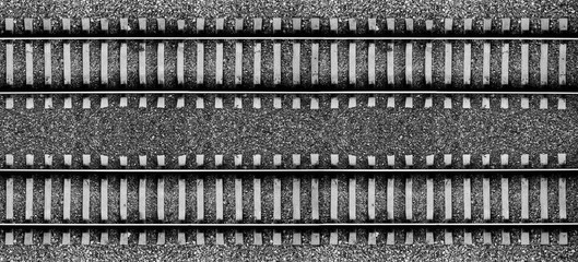 Black and white background with two railroad lines and gravel. View from above