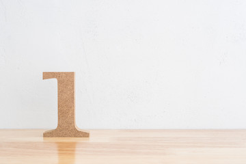 Wooden number one figure on wood table with white wall background and copy space. Concept of leader or winner competition.