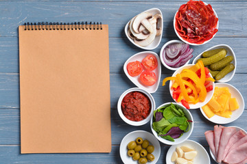 Ingredients for tasty pizza and notebook on wooden background