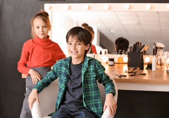 Cute little hairdresser working with client in beauty salon