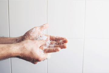 Fototapeta premium Man cleaning his hands using liquid disinfectant soap and water in bathroom.
