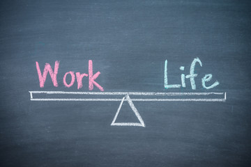 Work and life balance lifestyle management concept. Text word work and life handwriting on seesaw drawing on wooden chalkboard or blackboard.