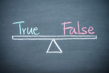 Text word true and false balance on seesaw drawing writing on chalkboard or blackboard background. Concept of true and false consideration in business management and investment. Real photo.