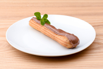 Traditional french dessert. Delicious eclair with custard and chocolate icing on a white plate with...