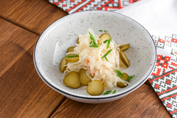 Sauerkraut. Sour cabbage salad served in white bowl over dark rustic wooden table background.