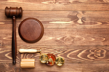 Judge's gavel, stamps and scales of justice on wooden background