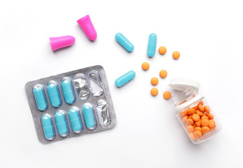 Ear plugs and sleeping pills on white background