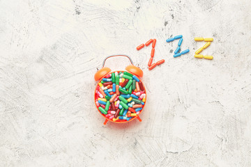 Alarm clock and sleeping pills on light background