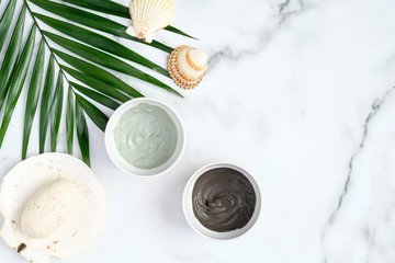 Facial clay mask and tropical leaf on marble background. Flat lay natural organic SPA cosmetic...