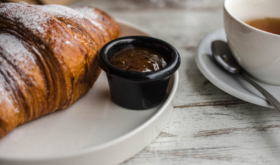 croissant with jam and tea on a white wooden background. background texture screensaver. photo with...