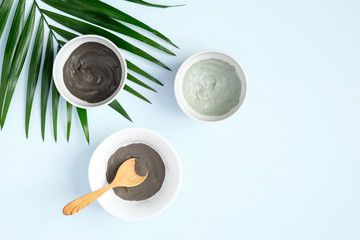 Flat lay facial clay mask and tropical leaf. Top view natural organic SPA cosmetic products for skincare, body and hair care concept