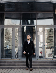 Fototapeta premium Portrait of fashionable well dressed man with beard posing outdoors
