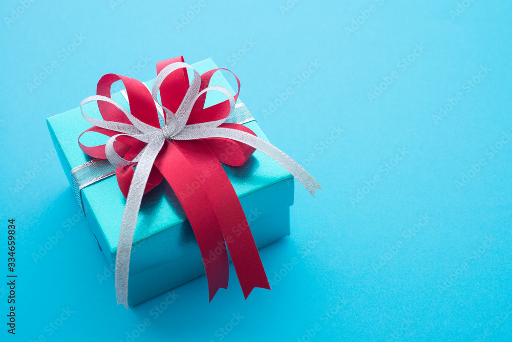 Wall mural top view of blue gift box with red white bow ribbon on blue background and copy space. credit card r