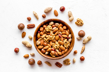 Mixed nuts in bowl on white background top-down