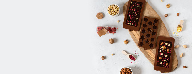 Chocolate banner. Dark chocolate bars and candies in molds with nuts and dried fruits on white...