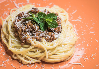 Traditional spaghetti bolognese on an orange plate