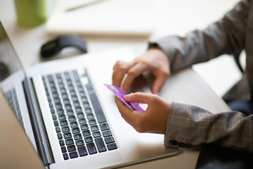 Obraz premium Young businesswoman holding a credit card and typing. On-line shopping on the internet using a laptop