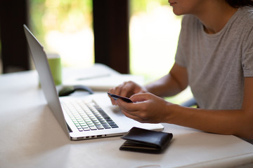 Close up of woman hands holding a credit card and typing. On-line shopping on the internet using a laptop