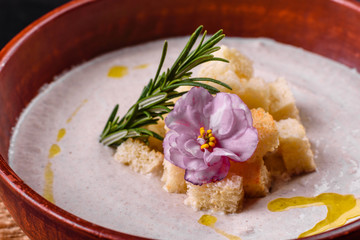 Delicious beautiful mushroom soup in a brown plate with a wooden spoon