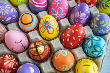 Fototapeta na wymiar close up rack of colorful vibrant easter egg with flower, stripe, spot and abstract patterns in green red pink purple, orange and blue colors, representing decoration and celebration of easter eggs
