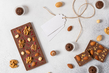 Milk chocolate bars and candies with nuts on light background. Homemade organic chocolate. Handmade tasty presents. Top view