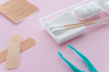Forceps, plasters, cotton ball, gauze ( Sterile dressing set ) on pink background. First aid kit at home, healthcare and medical concept.