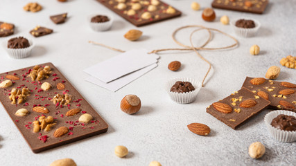 Handmade milk chocolate bars with nuts and dried fruits on white background. Side view, close up.