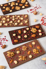 Variety of chocolate bars, nuts and ingredients on white wooden background. Handmade organic chocolate. Side view