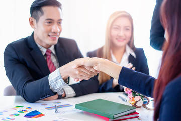 closeup of asian businessmen and business women shaking hands in partnership, working together in teamwork, planning strategies and decision making for the business or company to progress and succeed