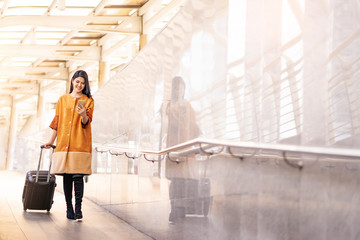 beautiful asian woman using a smartphone smiling looking and surfing on the internet while walking...