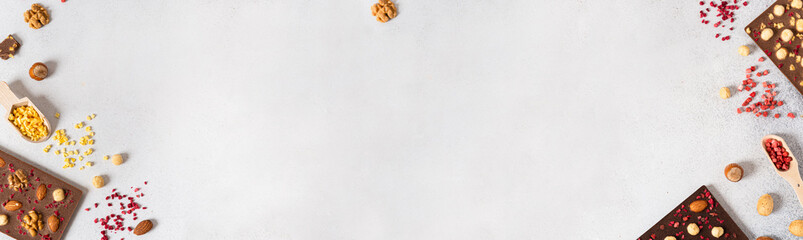 Variety of chocolate bars, nuts and ingredients on white wooden background. Handmade organic...