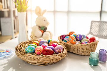 Fototapeta na wymiar colorful piles easter eggs basket of bird nest, paint cartilages paint pallets bunny soft toy and bright sunlight in background, representing decorating and painting eggs to celebrate easter holidays