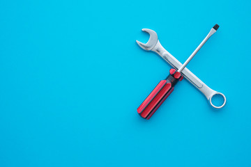 Flat lay of combination spanner or wrench and screwdriver on blue background with copy space. Customer care, after sales service and maintenance concept. After sales service to keep customer satisfied