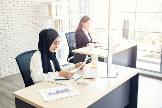 multiethnic asian female muslim working in office as team using documents of statistics to strategize and planning work concept of diversity of culture different race type people co-working together