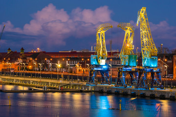 Illuminated old port cranes on a boulevard in Szczecin against the backdrop of storm clouds