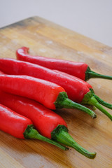 Close up shot of fresh red chilli pepper from top lay flat on yellow wood chopping board with copy space.