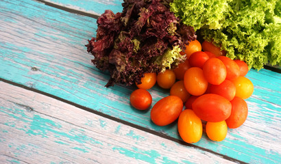 Tomato cherry with green and red leaf lettuce on top wooden table. Fresh ingredient for making...