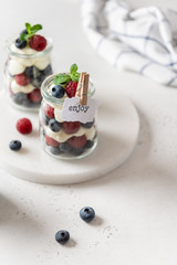 Berry yogurt with fresh strawberries and blueberries in jars. Healthy breakfast parfait in glass jars. Copy space for text. Summer dessert