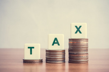 Word alphabet TAX on step stacked coins as graph up. Business, finance and tax concept. A tax is a compulsory financial charge by a governmental organization such as revenue department.